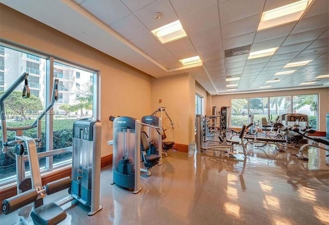 gym featuring baseboards and a paneled ceiling