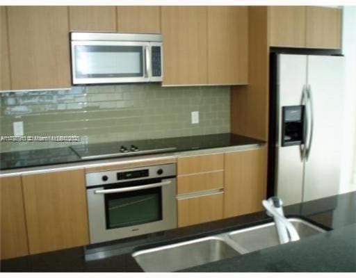 kitchen featuring appliances with stainless steel finishes, backsplash, dark countertops, and modern cabinets