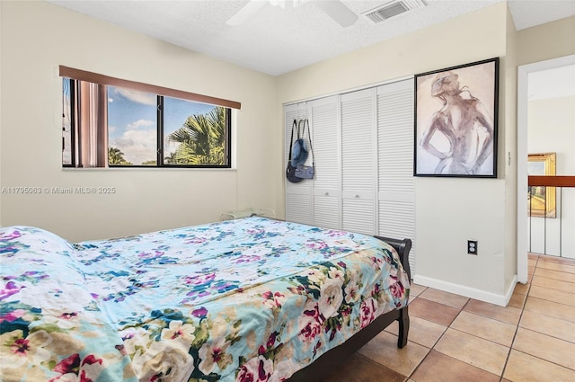 bedroom featuring a closet, a textured ceiling, visible vents, ceiling fan, and light tile patterned flooring