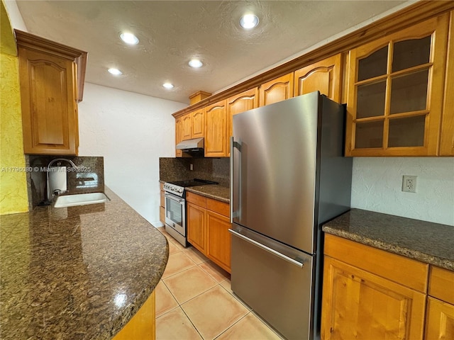 kitchen featuring a sink, recessed lighting, decorative backsplash, glass insert cabinets, and appliances with stainless steel finishes