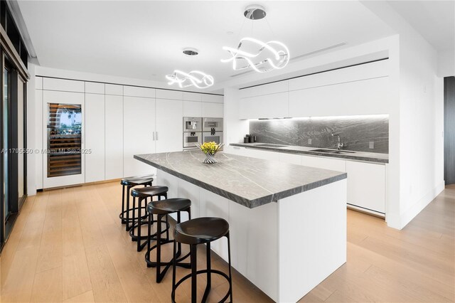 7025 Fisher Island Dr Unit 7025, Miami Beach, FL 33109 - kitchen with modern cabinets, dark countertops, white cabinetry, and a breakfast bar area