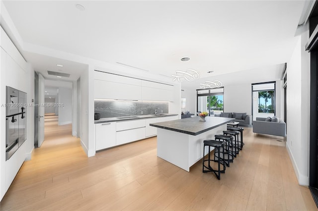 7025 Fisher Island Dr Unit 7025, Miami Beach, FL 33109 - kitchen featuring modern cabinets, dark countertops, a center island, a breakfast bar, and white cabinetry