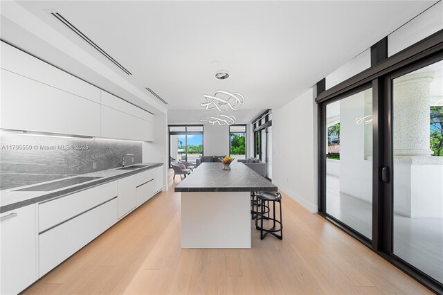 7025 Fisher Island Dr Unit 7025, Miami Beach, FL 33109 - kitchen featuring modern cabinets, dark countertops, white cabinetry, a sink, and black electric stovetop