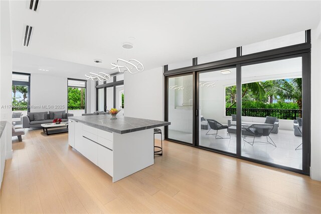 7025 Fisher Island Dr Unit 7025, Miami Beach, FL 33109 - kitchen with modern cabinets, white cabinets, light wood-style flooring, a kitchen island, and dark countertops