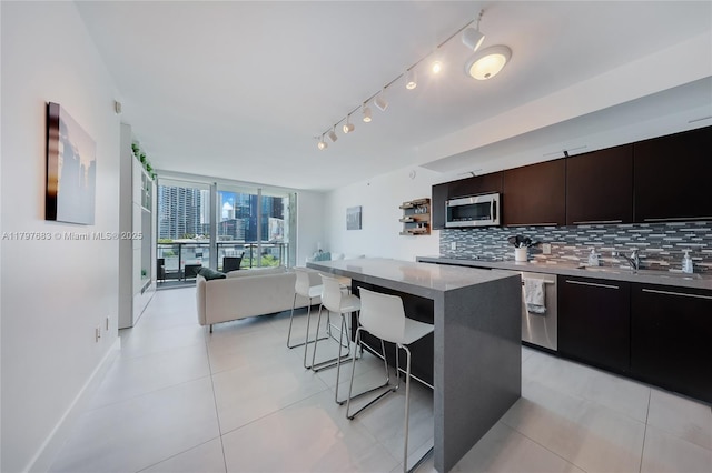 kitchen featuring stainless steel appliances, a kitchen breakfast bar, backsplash, open floor plan, and modern cabinets