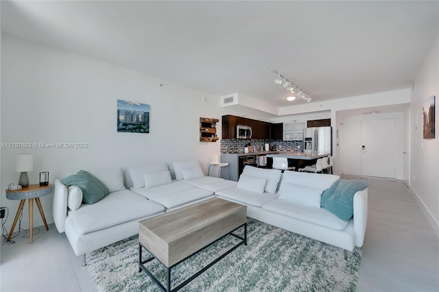 living room with rail lighting, visible vents, and baseboards