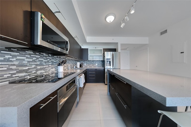 kitchen featuring light tile patterned floors, visible vents, modern cabinets, appliances with stainless steel finishes, and decorative backsplash