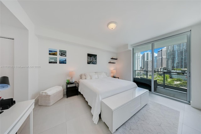 bedroom with light tile patterned floors, a wall of windows, and access to outside