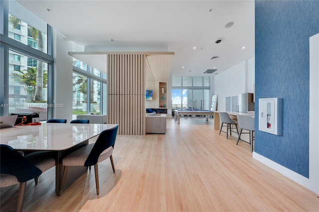 dining room featuring an accent wall, wallpapered walls, and light wood-style floors