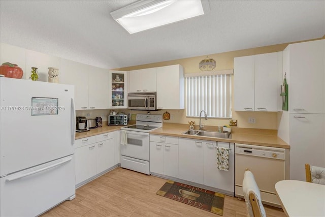 kitchen with light countertops, light wood-type flooring, a sink, and white appliances