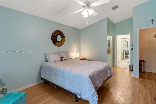 bedroom featuring lofted ceiling, baseboards, light wood-style flooring, and visible vents