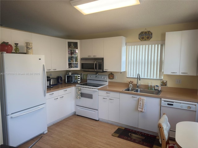 15773 NW 16th Ct, Pembroke Pines, FL 33028 - kitchen with white appliances, a sink, white cabinetry, glass insert cabinets, and light wood finished floors