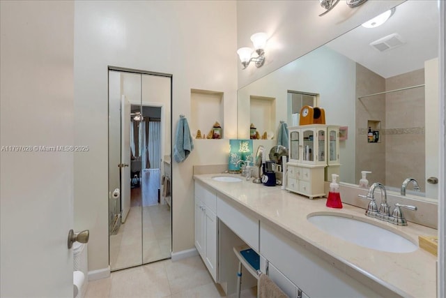 full bath featuring double vanity, tile patterned flooring, a tile shower, and a sink