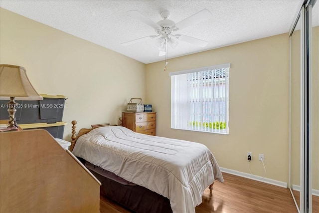 bedroom with baseboards, a ceiling fan, a textured ceiling, and wood finished floors