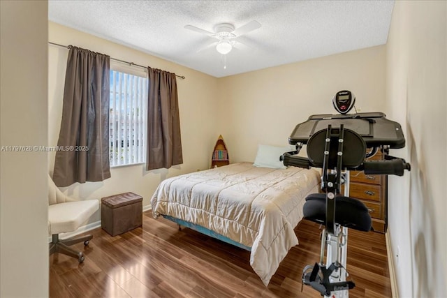 bedroom with baseboards, ceiling fan, a textured ceiling, and wood finished floors