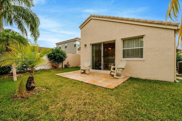 back of house featuring stucco siding, fence, a lawn, and a patio