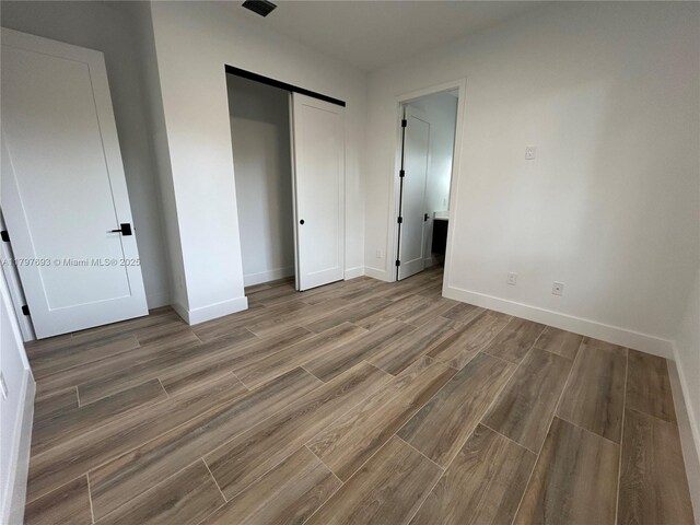 1611 SW 30th Ave, Fort Lauderdale, FL 33312 - unfurnished bedroom with wood finished floors, a barn door, baseboards, and a closet