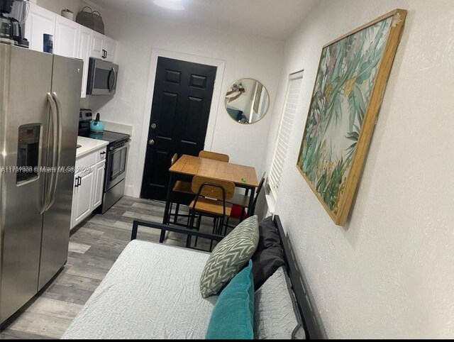 1860 NW 59th St, Miami, FL 33142 - kitchen featuring stainless steel appliances, white cabinetry, light countertops, light wood-type flooring, and a textured wall