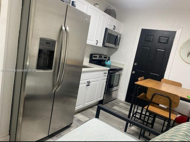 1860 NW 59th St, Miami, FL 33142 - kitchen featuring light wood finished floors, white cabinetry, light countertops, and appliances with stainless steel finishes