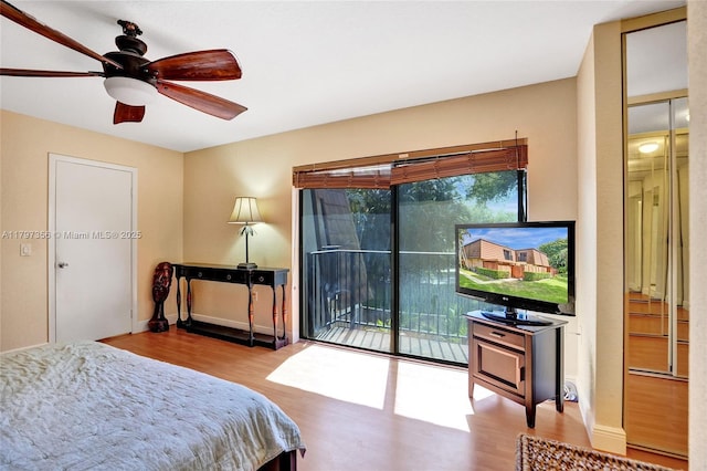 bedroom with a ceiling fan, baseboards, wood finished floors, and access to exterior