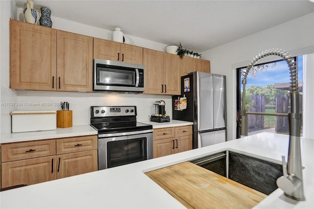 kitchen with light countertops, a sink, appliances with stainless steel finishes, and decorative backsplash
