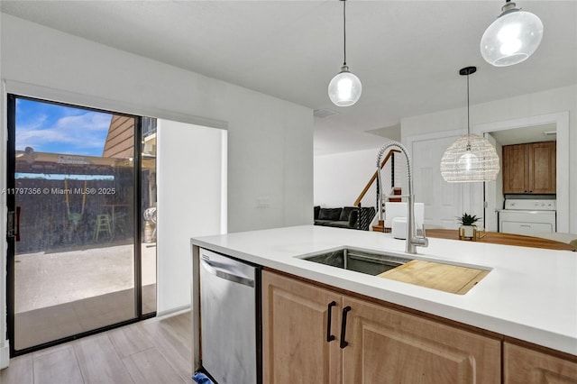 kitchen with light countertops, washer / dryer, a sink, and stainless steel dishwasher