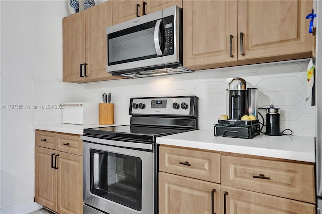 kitchen featuring light countertops, decorative backsplash, stainless steel appliances, and light brown cabinetry