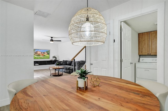 dining area featuring washer / clothes dryer, ceiling fan, visible vents, and wood finished floors
