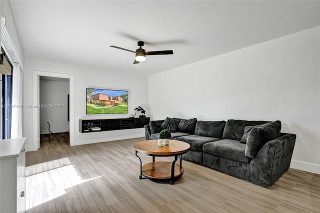 living room featuring baseboards, light wood finished floors, and ceiling fan