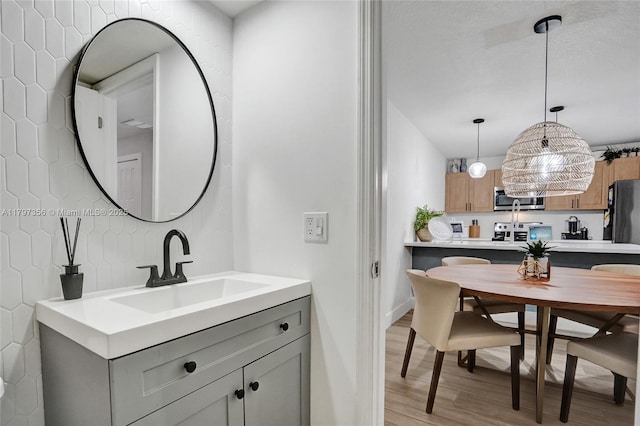 bathroom featuring vanity, decorative backsplash, baseboards, and wood finished floors
