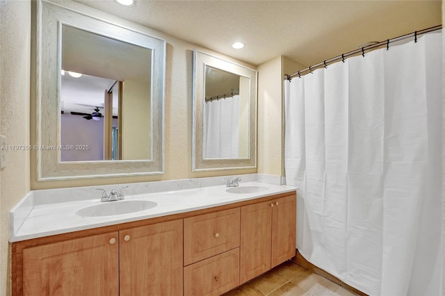 bathroom featuring a sink, double vanity, a textured wall, and tile patterned flooring