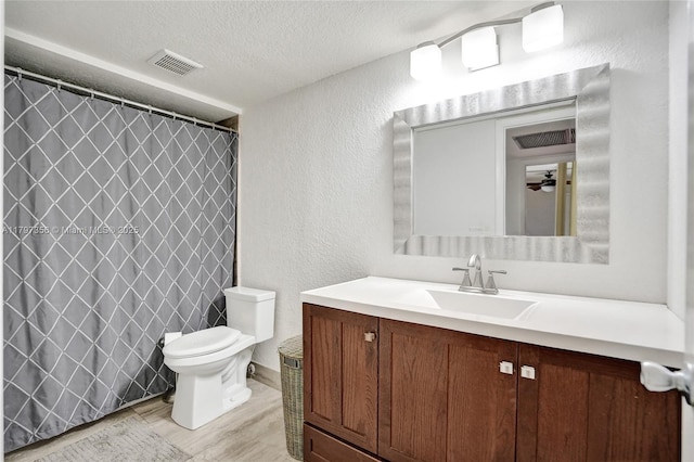 full bath with a textured ceiling, toilet, visible vents, vanity, and a textured wall