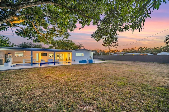 8501 SW 142nd St, Palmetto Bay, FL 33158 - back of house at dusk featuring a patio, stucco siding, a swimming pool, a fenced backyard, and a lawn