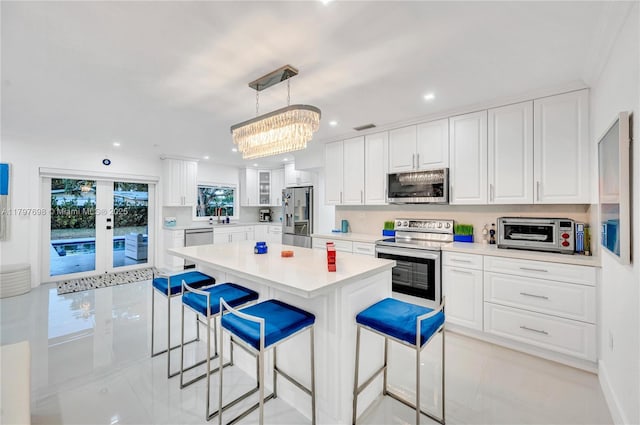 8501 SW 142nd St, Palmetto Bay, FL 33158 - kitchen with stainless steel appliances, a kitchen breakfast bar, white cabinets, light countertops, and recessed lighting