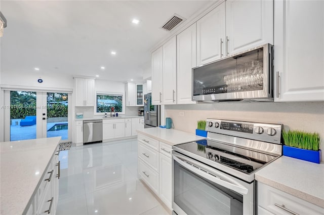 8501 SW 142nd St, Palmetto Bay, FL 33158 - kitchen with appliances with stainless steel finishes, light countertops, a sink, white cabinetry, and light tile patterned floors
