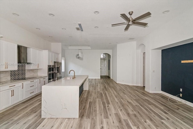 12471 NW 78th Mnr, Parkland, FL 33076 - kitchen featuring arched walkways, wall chimney range hood, open floor plan, white cabinetry, and recessed lighting