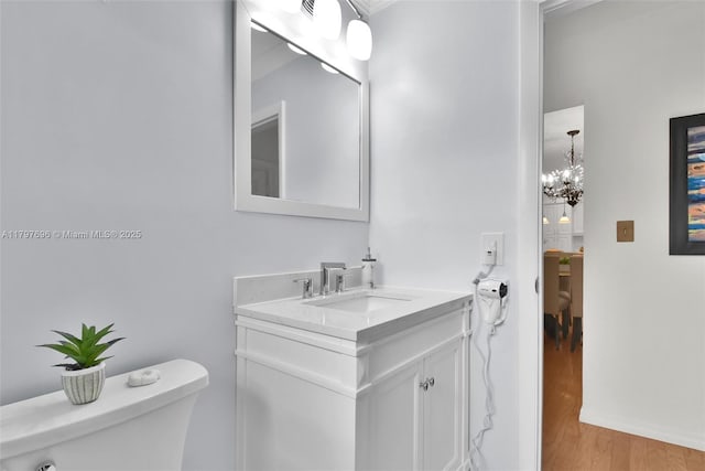 3921 Roosevelt St, Hollywood, FL 33021 - half bath with wood finished floors, a chandelier, vanity, and toilet