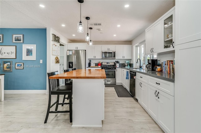 9652 NW 19th Pl, Sunrise, FL 33322 - kitchen with stainless steel appliances, butcher block counters, a kitchen breakfast bar, white cabinetry, and recessed lighting