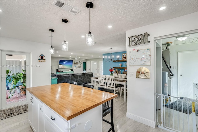 9652 NW 19th Pl, Sunrise, FL 33322 - kitchen with wood counters, light wood finished floors, white cabinets, a breakfast bar area, and a textured ceiling