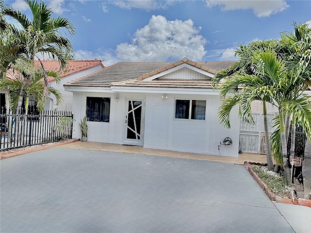 back of property featuring stucco siding, fence, and a tiled roof