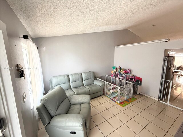 living area with light tile patterned floors, a textured ceiling, and lofted ceiling