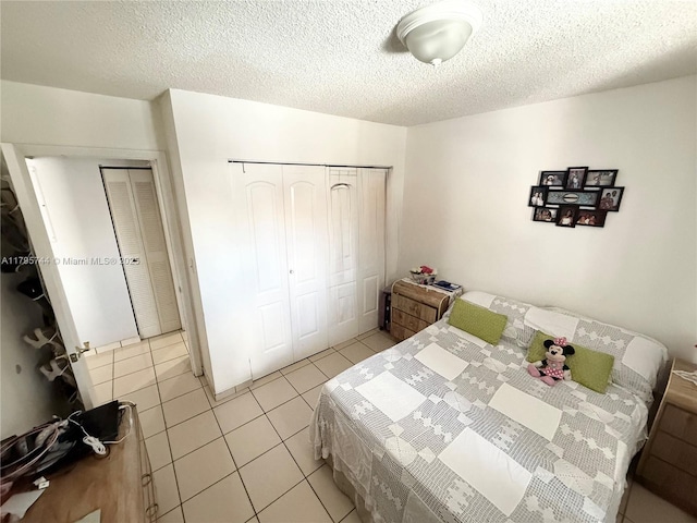 bedroom with a closet, light tile patterned floors, and a textured ceiling