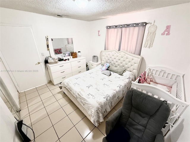 bedroom featuring a textured ceiling, light tile patterned floors, and visible vents
