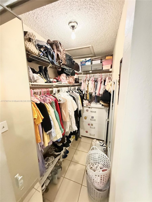 walk in closet with attic access and light tile patterned flooring
