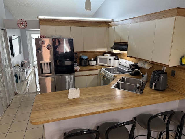 kitchen with ventilation hood, white appliances, a sink, and wooden counters