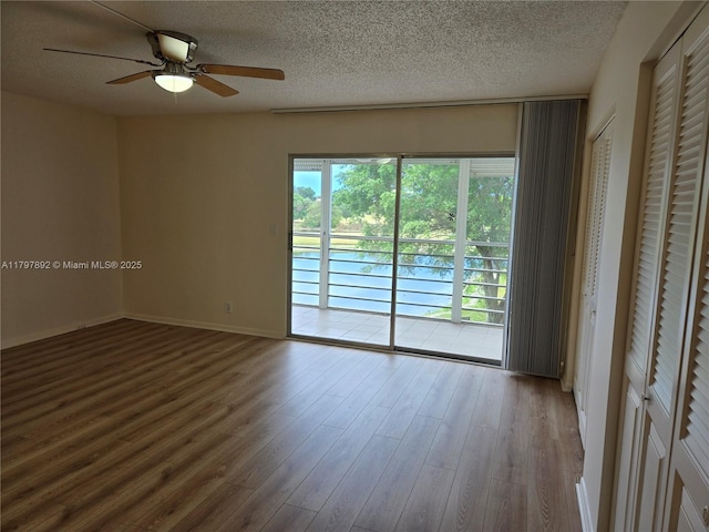 spare room with a textured ceiling, baseboards, a ceiling fan, and wood finished floors