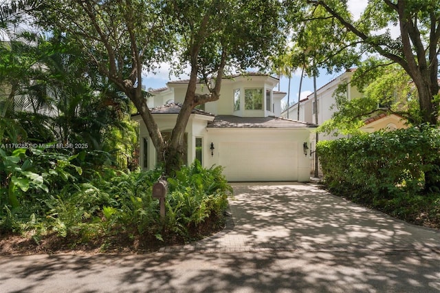 view of front of home with a garage, driveway, a tile roof, and stucco siding