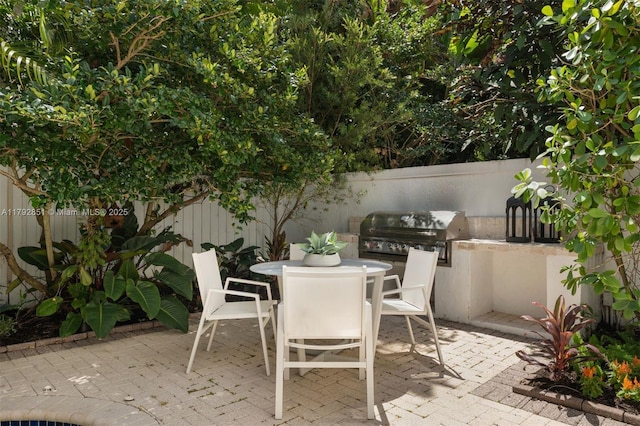 view of patio with a fenced backyard, grilling area, an outdoor kitchen, and outdoor dining space