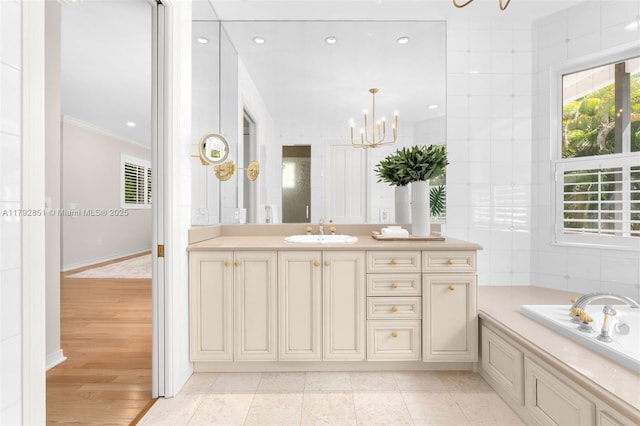 bathroom featuring an inviting chandelier, a bath, crown molding, vanity, and recessed lighting