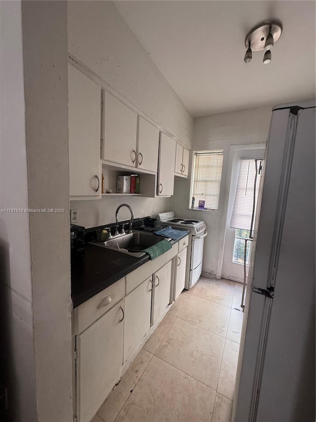 635 8th St Unit 103, Miami Beach, FL 33139 - kitchen featuring a sink, white appliances, light tile patterned flooring, white cabinets, and dark countertops
